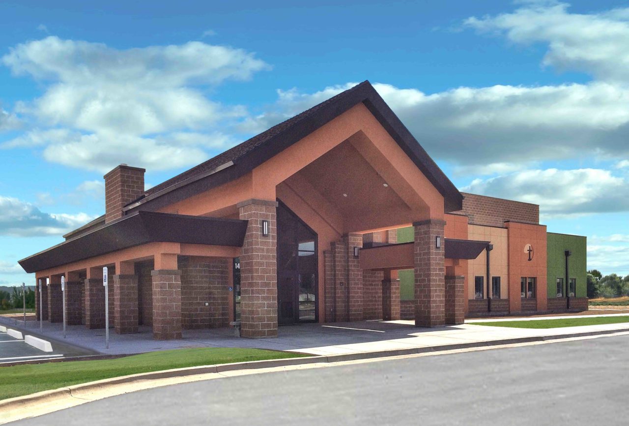 Idaho worship and community center. Church architecture church design. Mountain West Architects. Brick church exterior. Storefront church entrance. Gabled roof overhang church entrance.