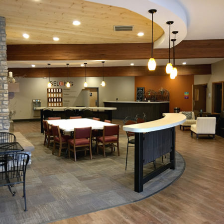 Pendant lightning, church foyer and lobby area, exposed wood framing, church café, warm church cafe color scheme, stone column, wood floor finish, wood ceiling